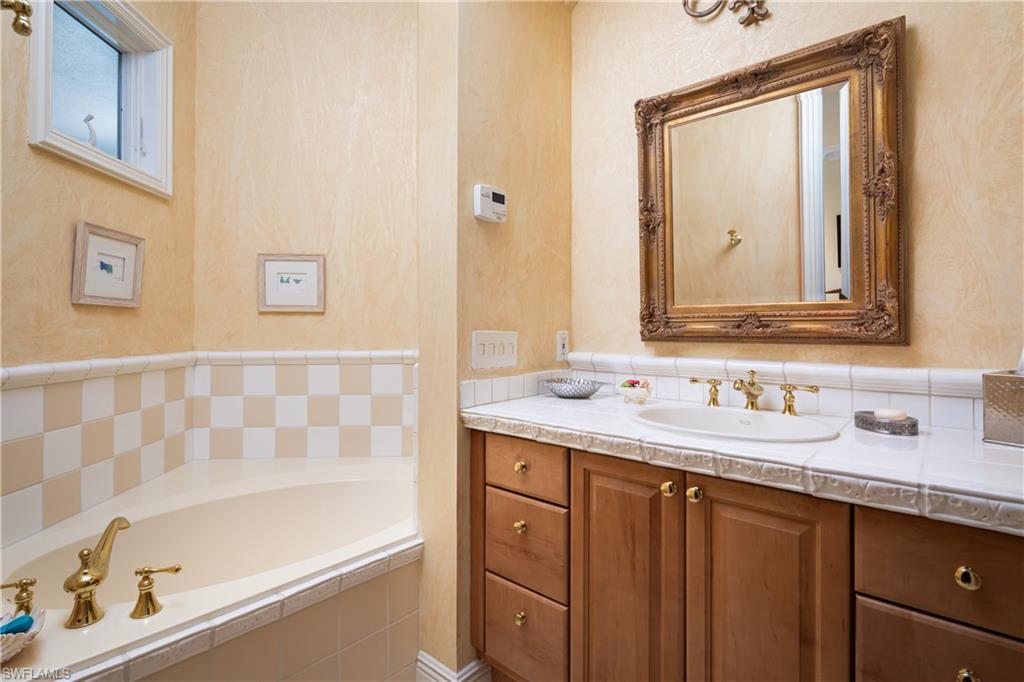980 Barcarmil Way Naples, FL 34110 - Photo 30 of 50 a bathroom with a tub a sink and a large mirror