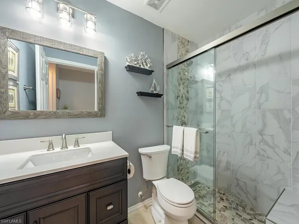 a bathroom with a sink a toilet a mirror and shower