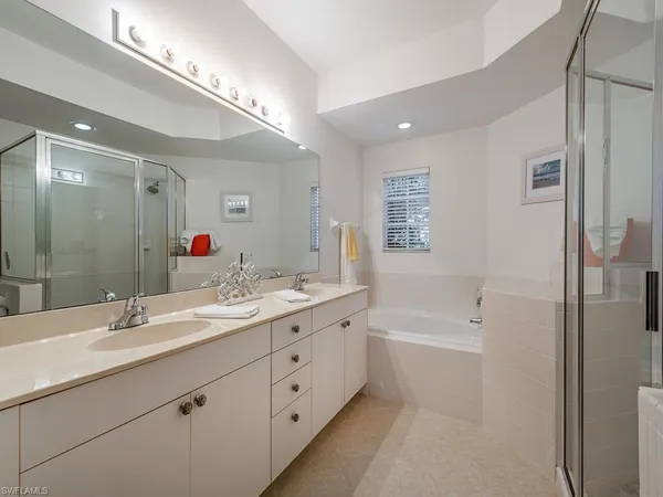 a bathroom with a double vanity sink a mirror a bathtub and shower