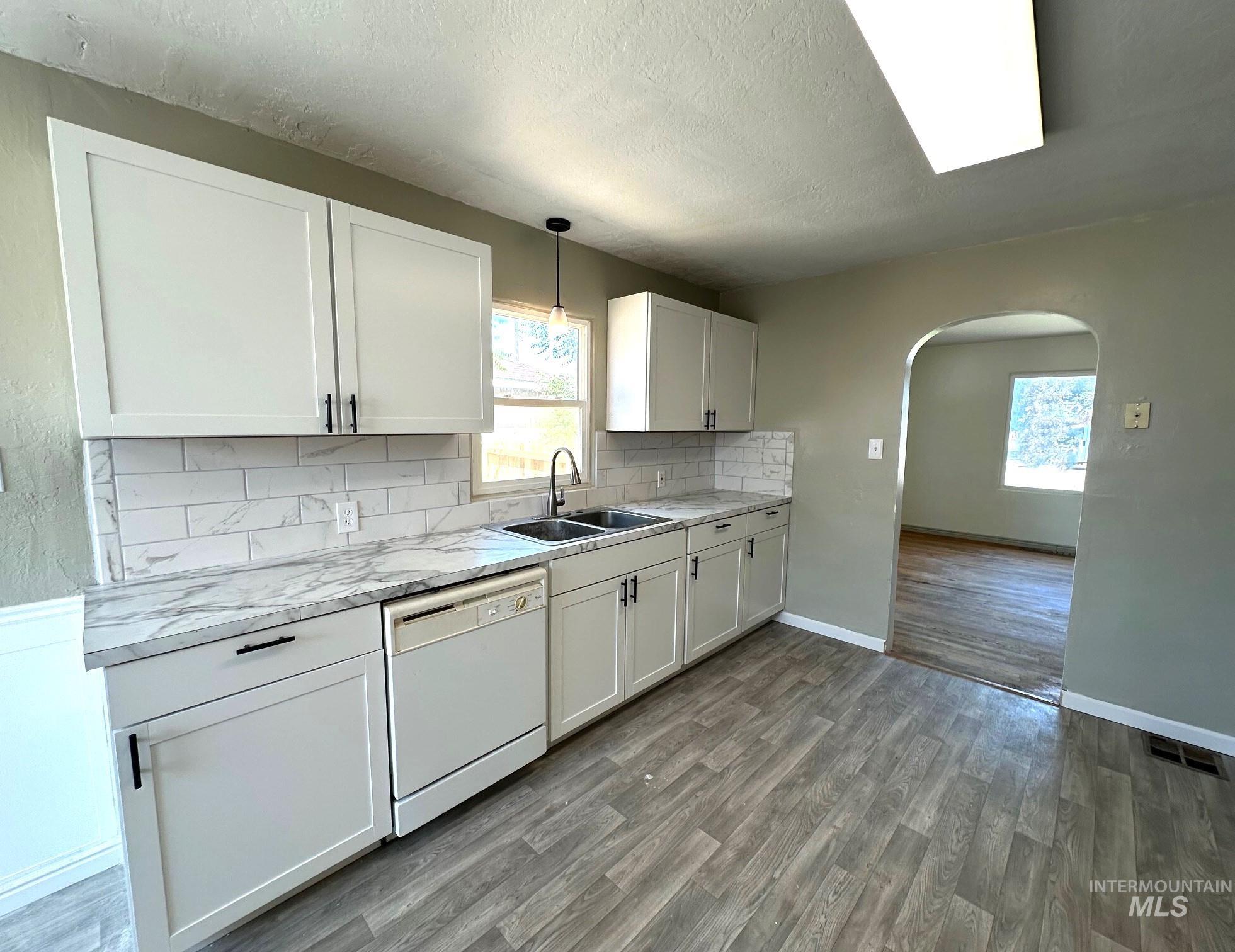 264 Southwest 10th Avenue Ontario, OR 97914 - Photo 6 of 29 Kitchen featuring arched walkways, white dishwasher, healthy amount of natural light, wood finished floors, and a textured ceiling
