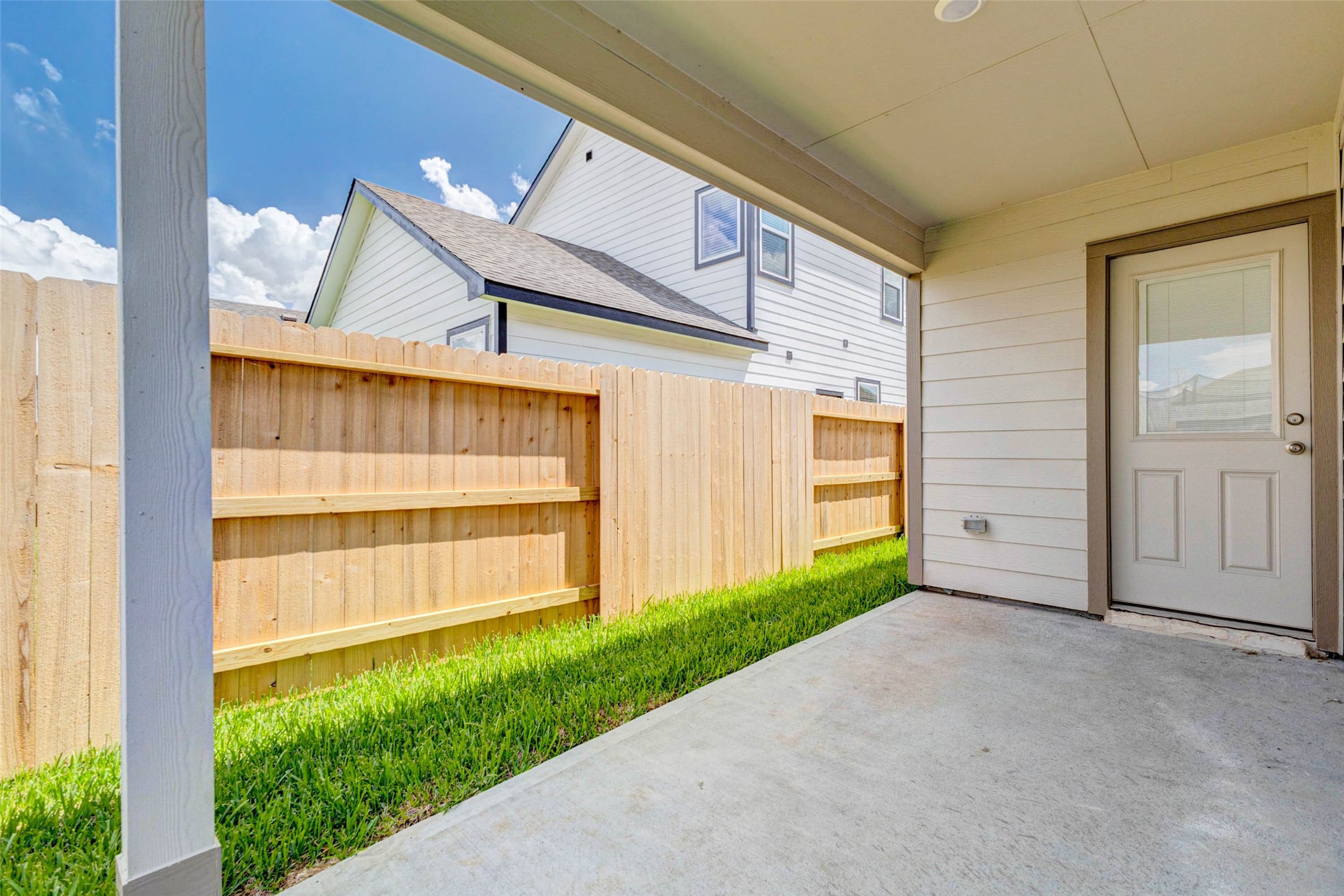 6467 Escondido Drive Rosharon, TX 77583 - Photo 28 of 32 Covered back patio with concrete slab, rear entry door, privacy fence, and a narrow grassy side yard. This shaded outdoor space is ready for patio furniture, a grill, potted plants, or a cozy seating area, creating an easy transition from indoor living to private outdoor enjoyment.
