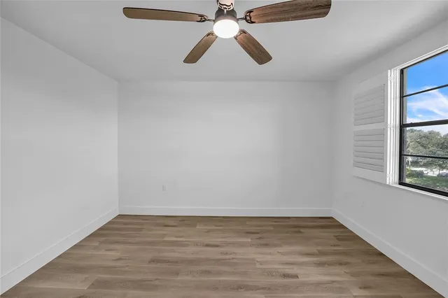 a view of an empty room with window and wooden floor