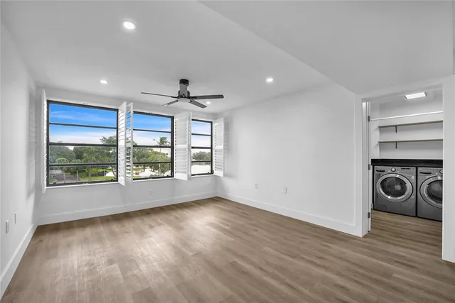 a view of empty room with wooden floor and fan
