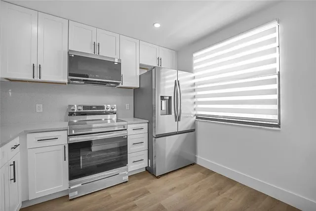 a kitchen with white cabinets and stainless steel appliances