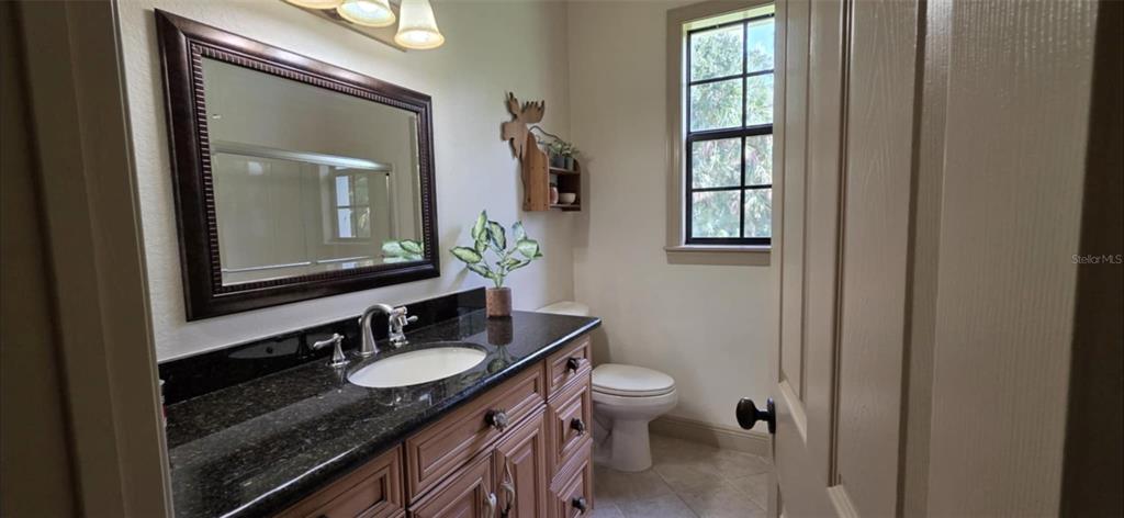 8991 Southwest Springhaven Avenue Indiantown, FL 34956 - Photo 21 of 30 a bathroom with a granite countertop sink a toilet and mirror