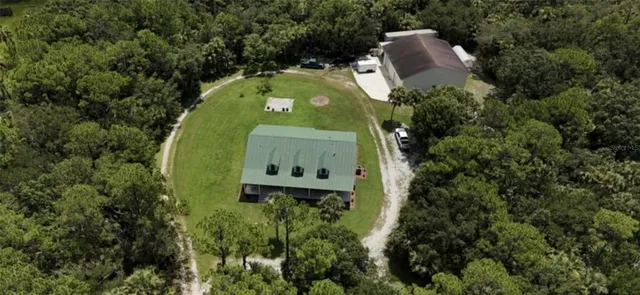 an aerial view of a house with a yard and trees all around