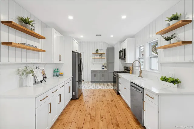a large white kitchen with stainless steel appliances lots of counter space and wooden floor