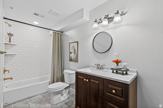 681 Island Road Morgan, UT 84050 - Photo 22 of 49 Bathroom featuring a white subway tile shower surround with gold-finish fixtures, a dark wood-finish vanity with a light-colored countertop, and a round wall mirror