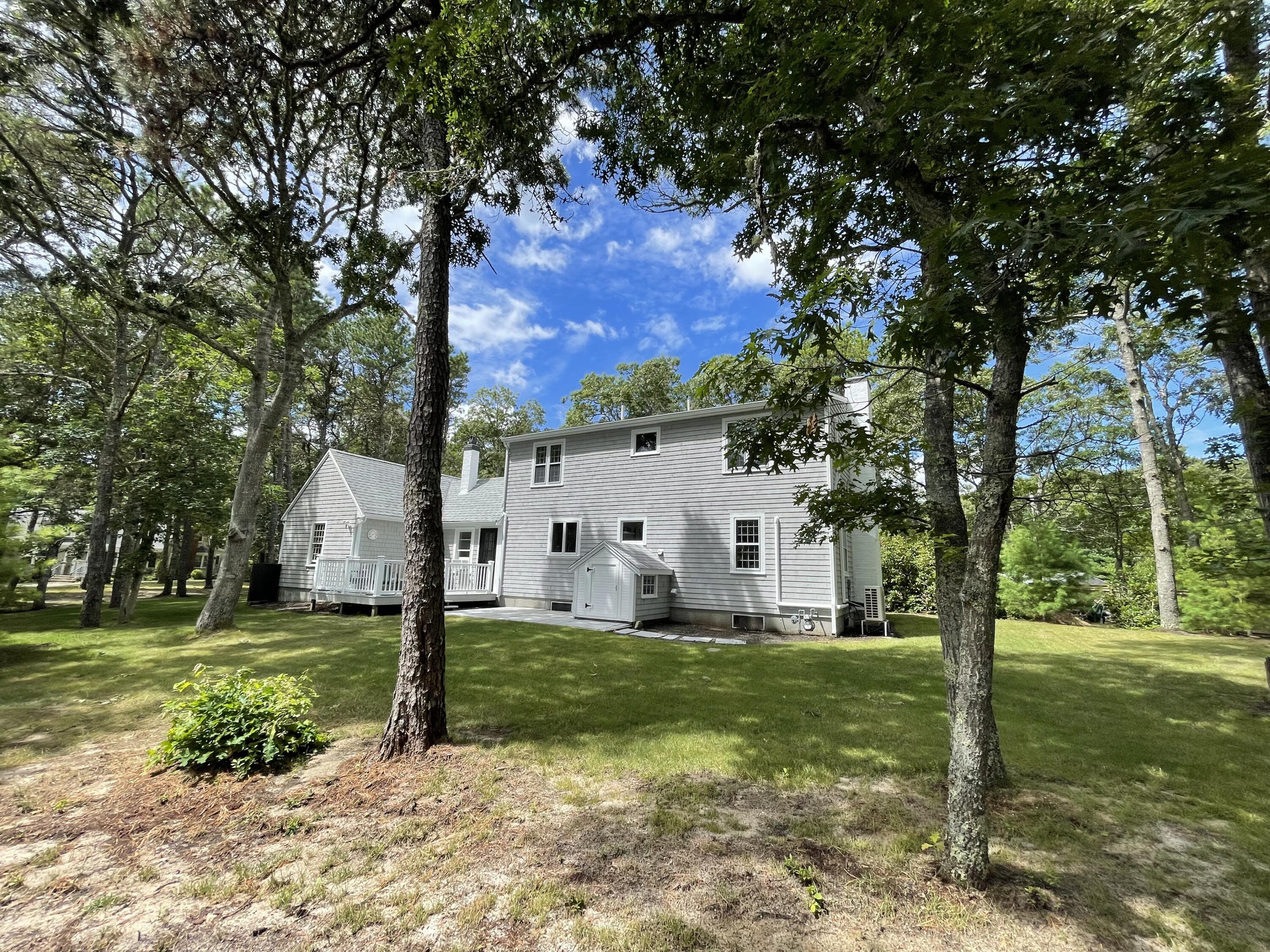 863 Bumps River Road Centerville, MA 02632 - Photo 5 of 22 a view of a white house with a big yard and large trees