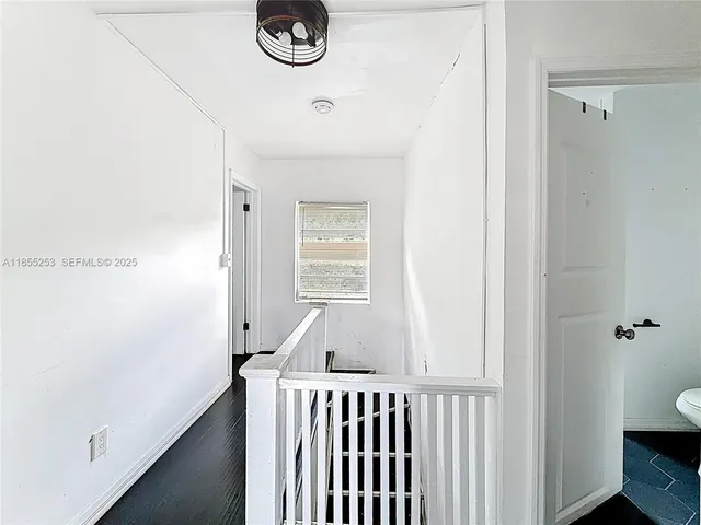 a view of a hallway to a bedroom with wooden floor and a window