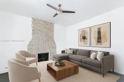 a living room with furniture a fireplace and a ceiling fan