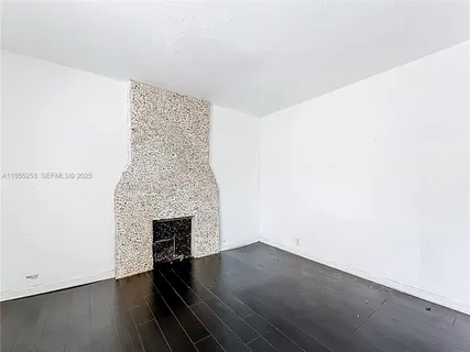 a view of an empty room with wooden floor and a fireplace