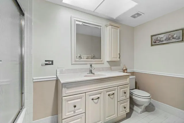 a bathroom with a granite countertop toilet sink and mirror