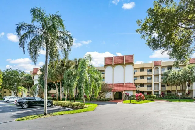 a front view of multi story residential apartment building with yard and sign board