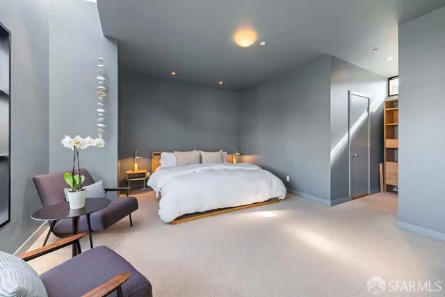 a bedroom with a bed a chair and potted plant on the table