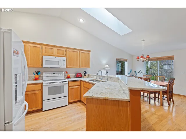 a kitchen with stainless steel appliances kitchen island granite countertop a table chairs sink and cabinets