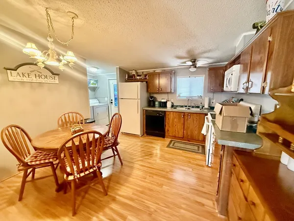 a kitchen with stainless steel appliances granite countertop a stove top oven a sink dishwasher and a dining table with wooden floor
