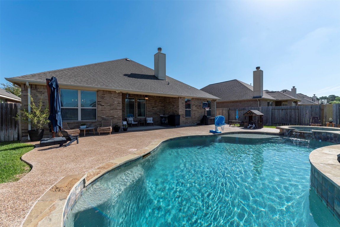 Stunning backyard oasis featuring a sparkling pool and spa with ample patio space—perfect for entertaining or relaxing.