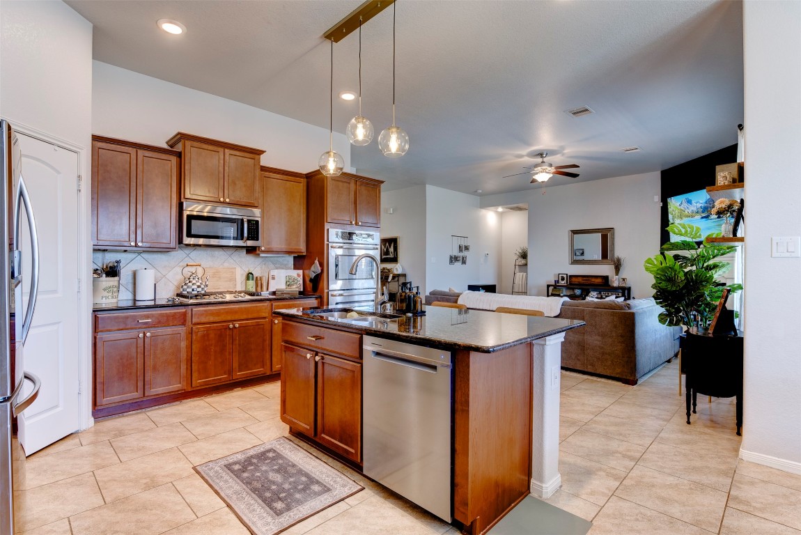 22939 Banff Brook Way Tomball, TX 77375 - Photo 10 of 25 Beautiful kitchen featuring granite countertops, stainless steel appliances, ample cabinetry, and a large island overlooking the living area.