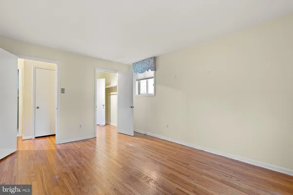 a view of an empty room with wooden floor and windows