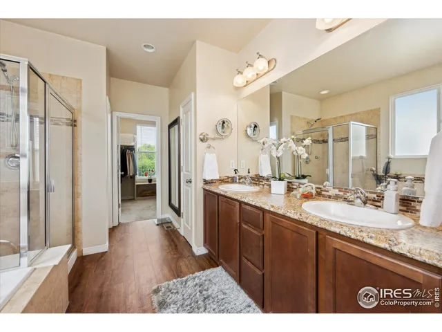 a bathroom with a sink double vanity granite tub shower and a mirror