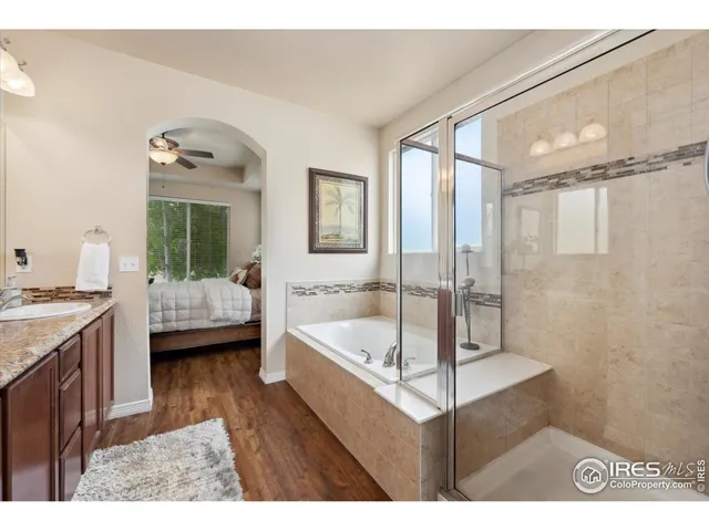 a en suite bathroom with a granite countertop tub sink a mirror and shower