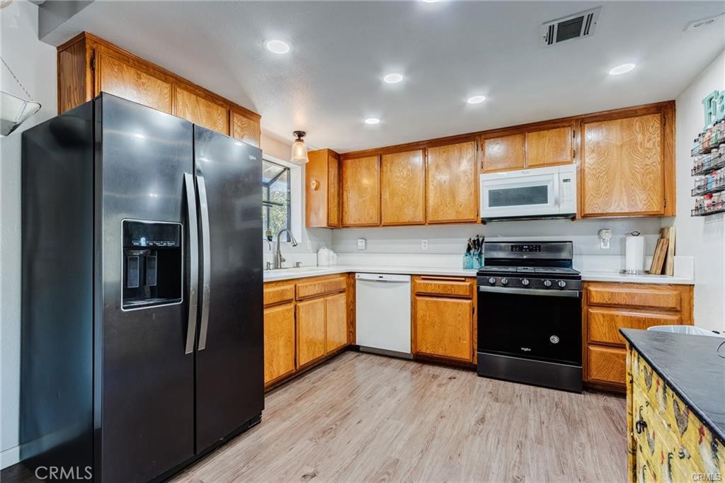 10971 Adobe Road Oak Hills, CA 92344 - Photo 21 of 49 a kitchen with stainless steel appliances granite countertop a refrigerator a sink dishwasher a oven with wooden cabinets and floor