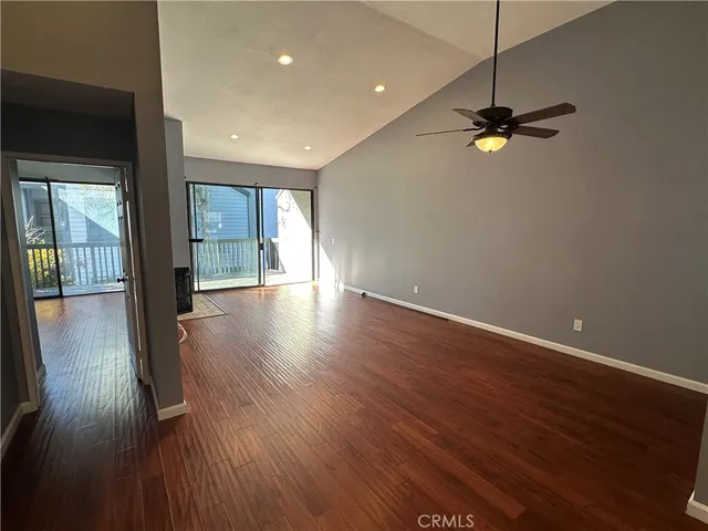 a view of empty room with wooden floor and fan