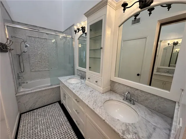 a bathroom with a granite countertop bathtub shower sink vanity and mirror
