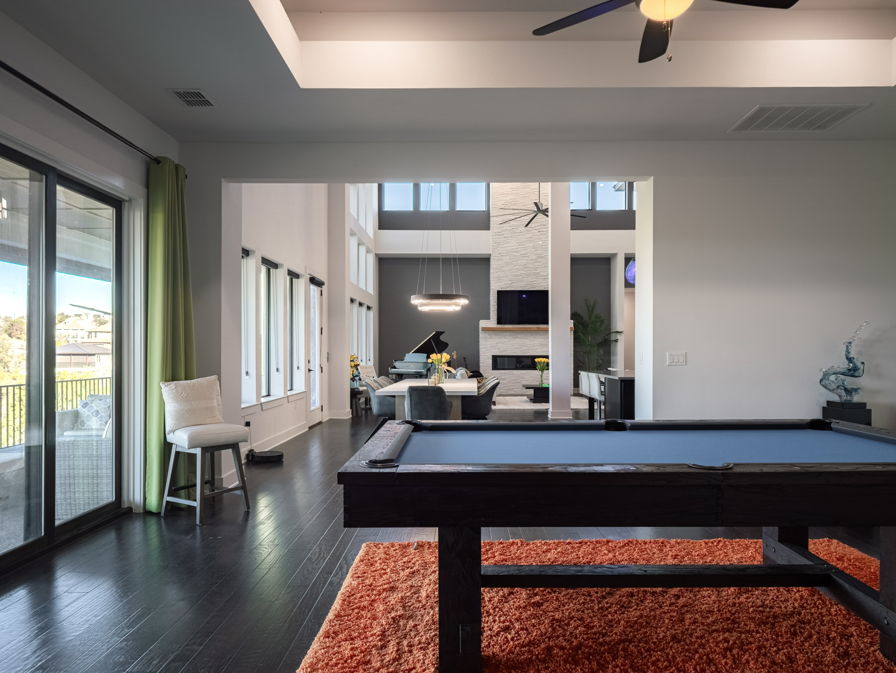 14900 Copper Ridge Lane Austin, TX 78734 - Photo 14 of 39 Game room featuring ceiling fan, dark wood-style flooring, a glass covered fireplace, a towering ceiling, and billiards