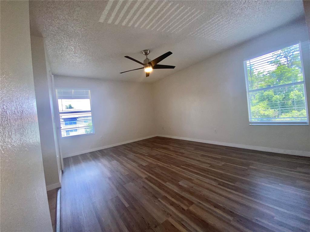 5144 Conroy Road, Unit 38 Orlando, FL 32811 - Photo 27 of 49 an empty room with wooden floor chandelier fan and windows