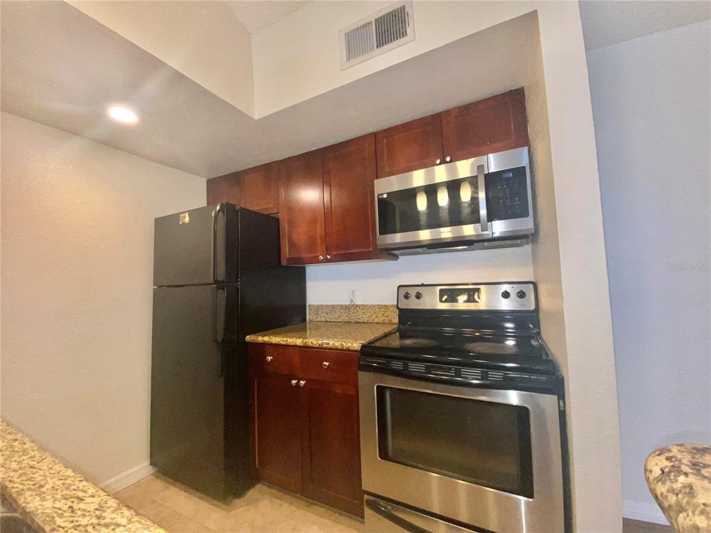 5144 Conroy Road, Unit 38 Orlando, FL 32811 - Photo 6 of 49 a kitchen with granite countertop a refrigerator stove and microwave