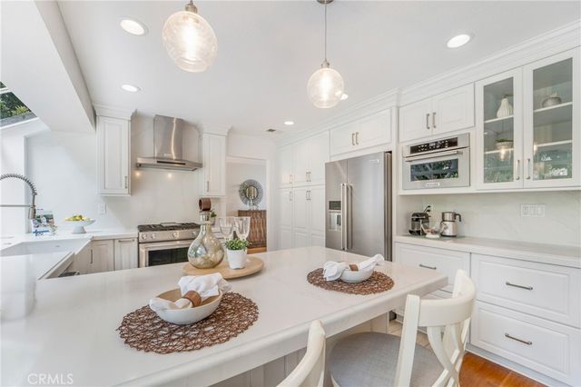 a kitchen with stainless steel appliances kitchen island granite countertop a dining table and chairs with wooden floor