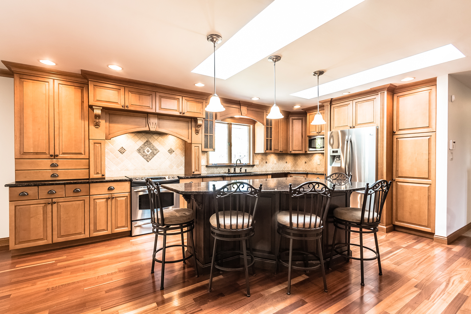 18802 West Manhattan Road Elwood, IL 60421 - Photo 8 of 38 a kitchen with stainless steel appliances granite countertop a table chairs sink and wooden floor