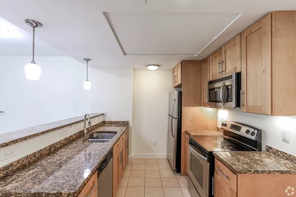 a kitchen that has a sink stainless steel appliances granite counter tops and a view of living room