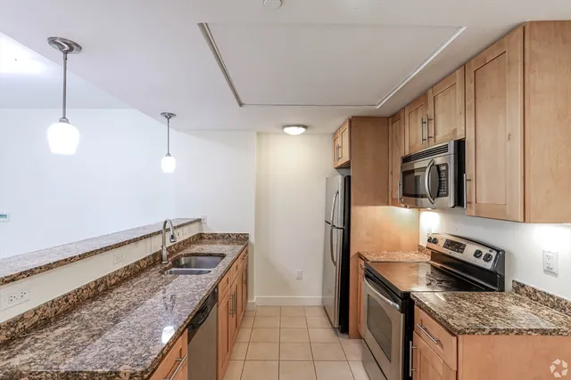 a kitchen that has a sink stainless steel appliances granite counter tops and a view of living room
