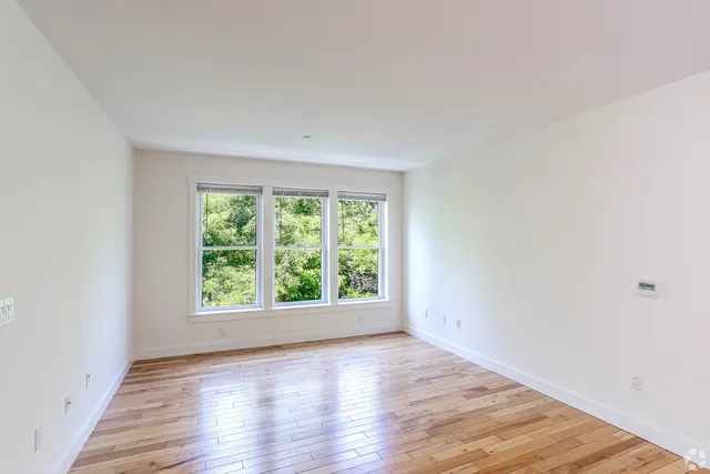 an empty room with wooden floor and window