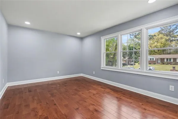 a view of an empty room with wooden floor and a window
