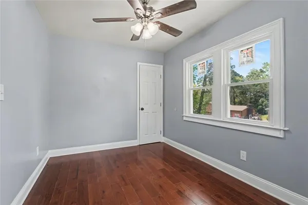 a view of an empty room with wooden floor and a window