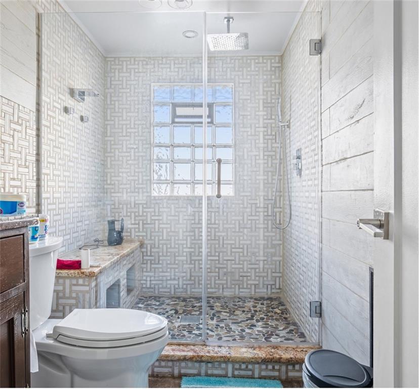 a bathroom with a granite countertop toilet a sink a shower and a mirror