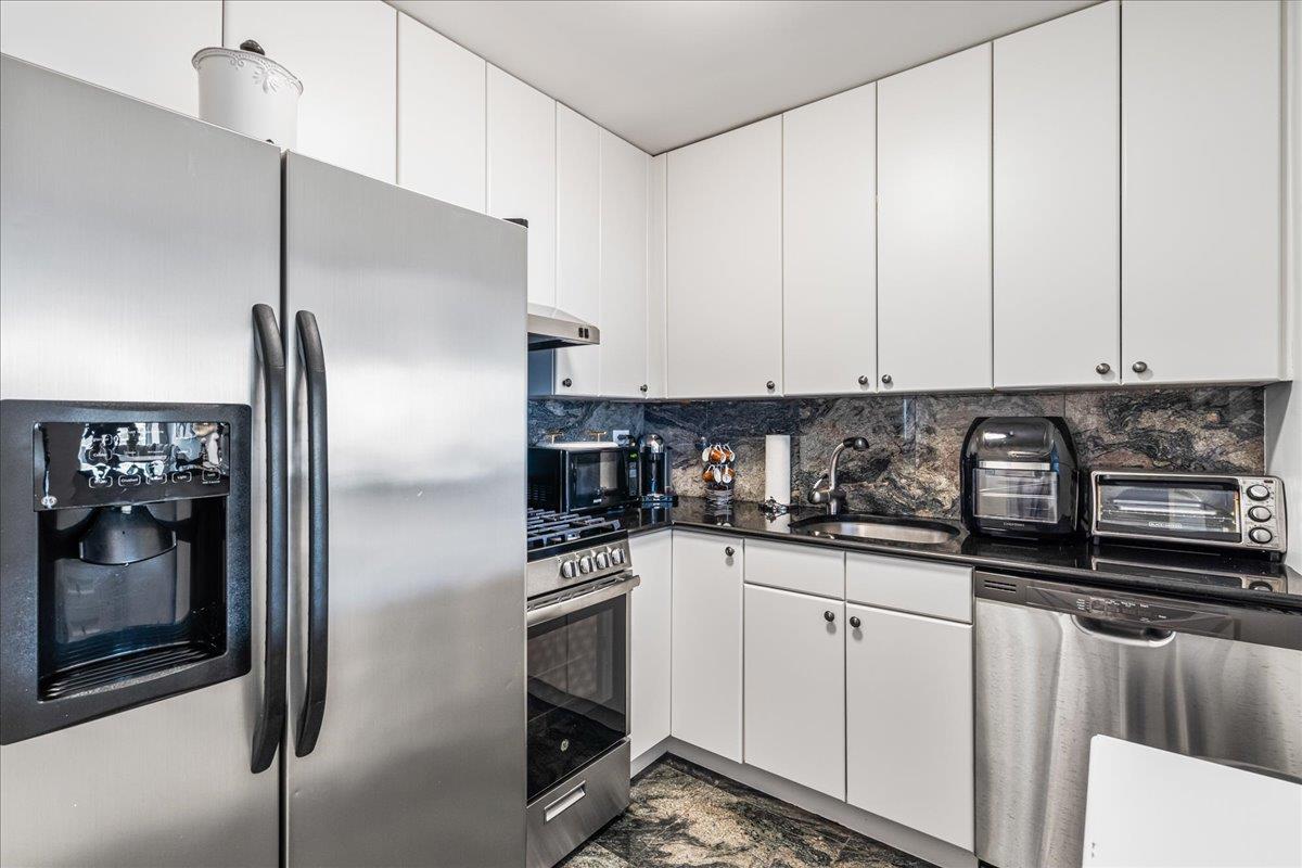 17-85 215th Street, Unit 16J Queens, NY 11360 - Photo 10 of 28 a kitchen with stainless steel appliances granite countertop a refrigerator a stove and a sink with wooden floor