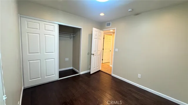 an empty room with wooden floor and closet area