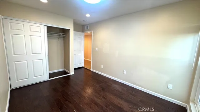 an empty room with wooden floor and closet area