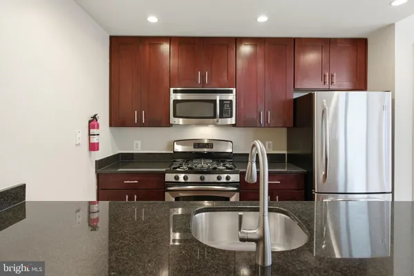 a kitchen with granite countertop a refrigerator stove and microwave
