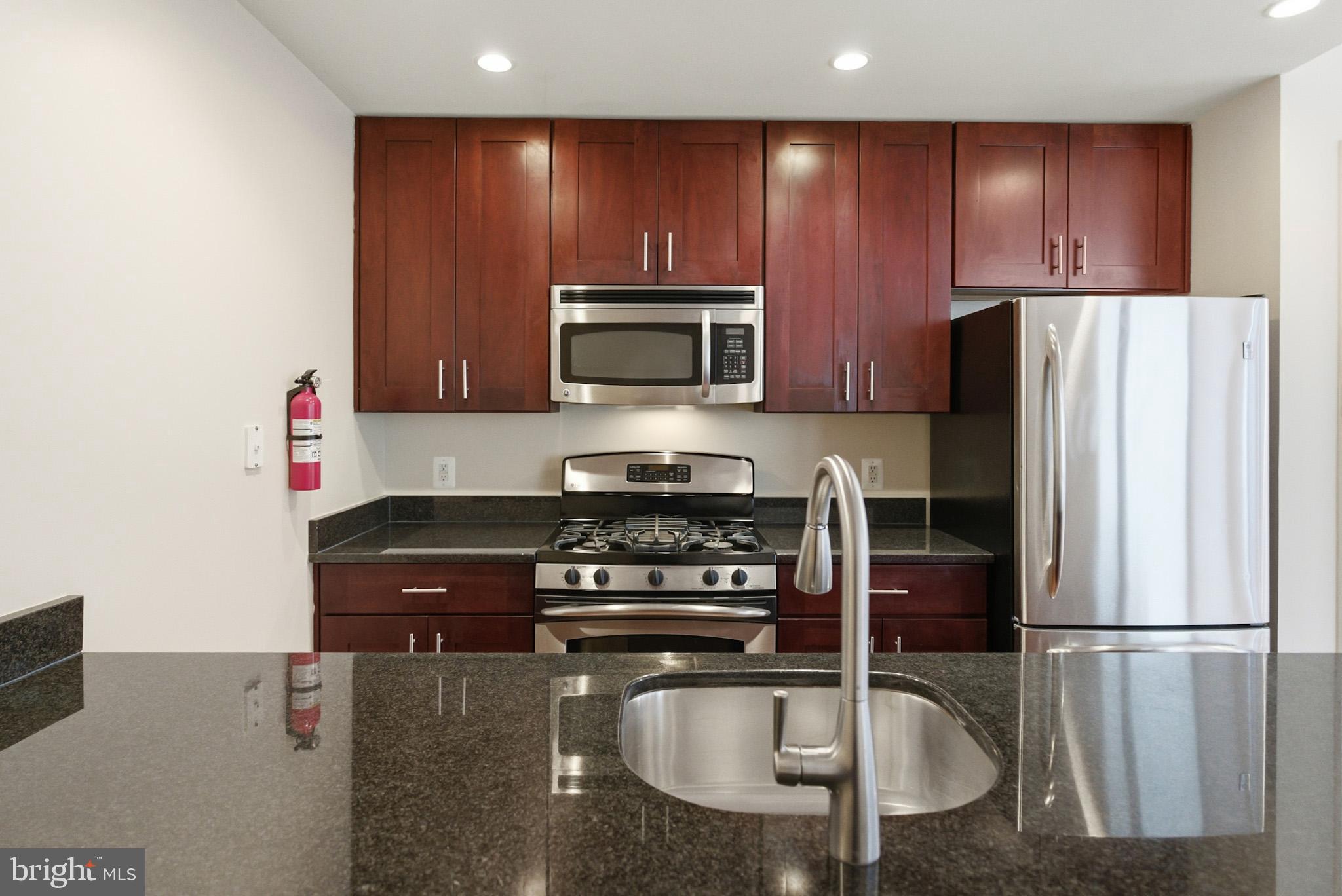1211 13th Street Northwest, Unit 206 Washington, DC 20005 - Photo 8 of 22 a kitchen with granite countertop a refrigerator stove and microwave