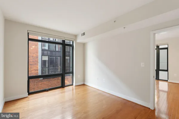 a view of empty room with wooden floor and fan