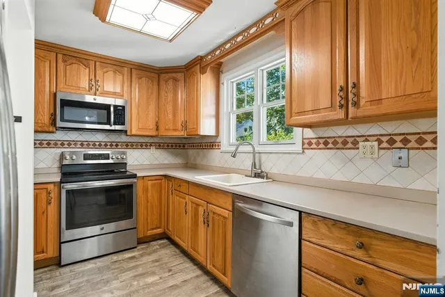 a kitchen with granite countertop a sink stainless steel appliances and cabinets
