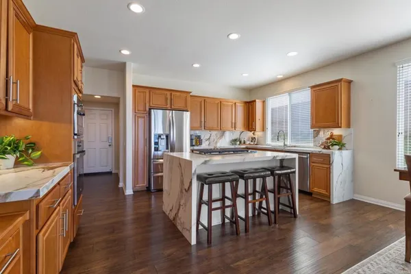 a kitchen with a refrigerator a stove and a dining table with wooden floor