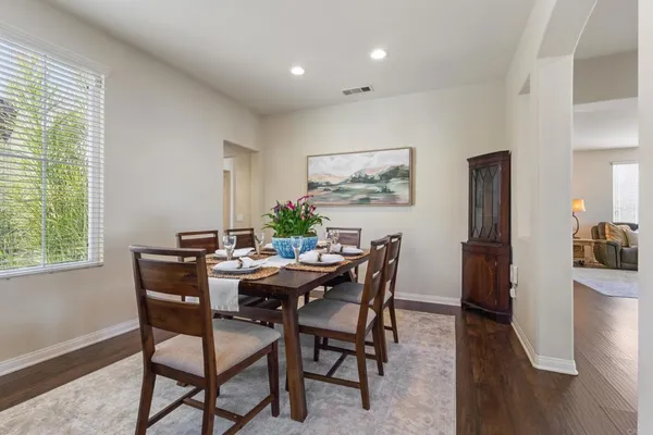 a kitchen with stainless steel appliances granite countertop a refrigerator a sink dishwasher a stove and a dining table with wooden floor
