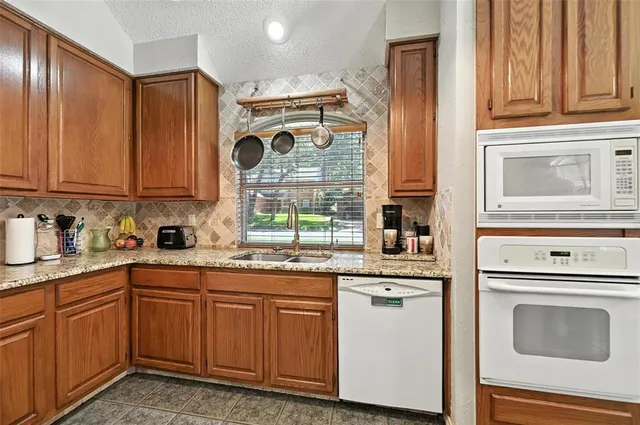 a kitchen with stainless steel appliances granite countertop a sink and cabinets with wooden floor